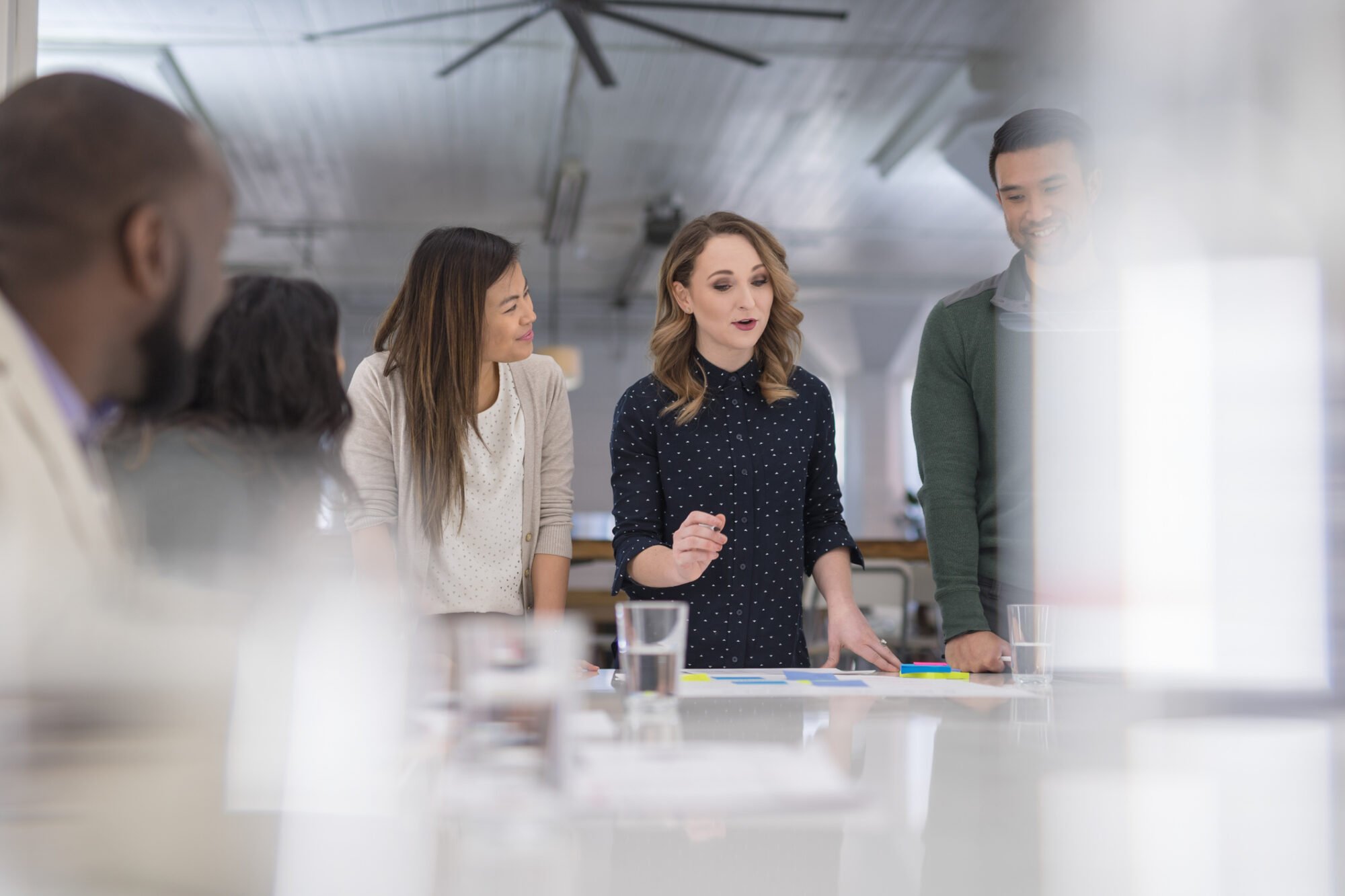 A mixed-ethnic group of business colleagues sign paperwork at the conference table